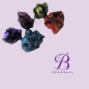 Assorted colorful bath bombs arranged on a pale lavender background with bath bomb beauties logo in the bottom right