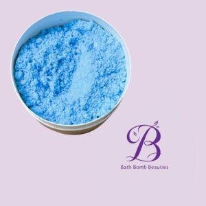 Blue bath bomb powder in a white round container on a light purple background with Bath Bomb Beauties logo nearby