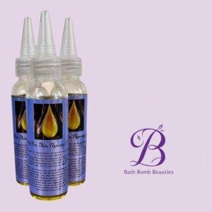 Three clear dropper bottles with blue label art showing a yellow flame, set on a lavender background; Bath Bomb Beauties logo visible bottom right.