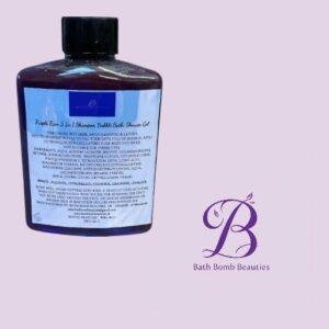 Dark purple bottle of Bath Bomb Beauties body wash on a light lavender background, with a purple 'B' logo and 'Bath Bomb Beauties' text nearby.