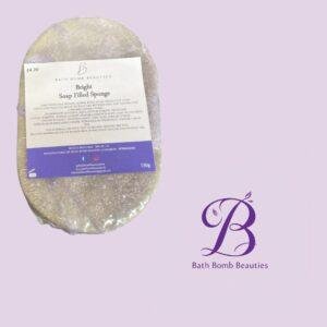 Bright Soap Filled Sponge by Bath Bomb Beauties shown on a lavender background with the brand logo in the corner on the right side.