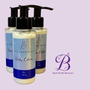 Three bath bomb beauties body lotion bottles with pump dispensers in a row against a pastel purple background logo visible in the lower right corner