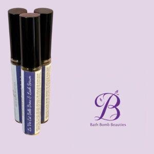 Three black-capped cylindrical bottles with blue labels standing upright against a lavender background, featuring Bath Bomb Beauties branding in the corner.