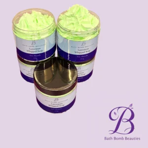 Two open jars of bright green whipped soap with purple labels reading Bath Bomb Beauties Luxurious Whipped Soap on a lavender background.