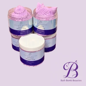 Two jars of lavender-pink Luxurious Whipped Soap from Bath Bomb Beauties, Berry Comfort scent, against a light purple background.