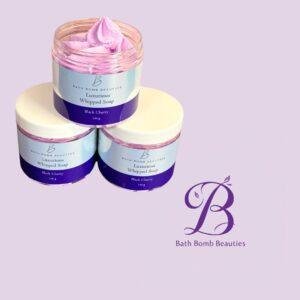 Three bath bomb beauties luxurious whipped soap jars black cherry stacked on a lavender background with the brand logo
