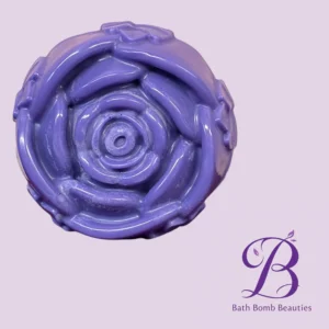 Close-up of a purple bath bomb on a light lavender background, with the 'Bath Bomb Beautie' logo partially visible to the right.
