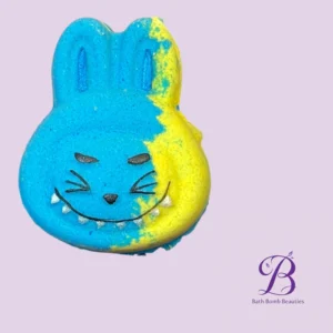 Blue and yellow bunny shaped bath bomb with a smiling face on a lavender background bath bomb beauties branding in the corner