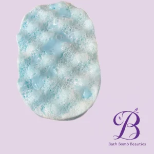 Blue foamy bath bomb on a pale purple background with the bath bomb beauties logo in the bottom right corner