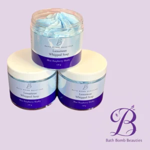 Three stacked bath bomb jars with blue whipped soap labels reading Luxurious Whipped Soap and Blue Raspberry Slushy, on a lavender background.