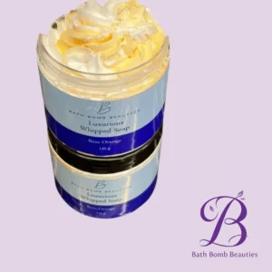 Two lavender-scented jars labeled 'Luxurious Whipped Soap' in Boss Orange, topped with whipped cream, on a pastel lavender background with Bath Bomb Beauties logo.