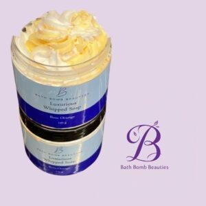 Jar of bath bomb beauties luxurious whipped soap with yellow whipped cream top against a lavender background logo visible on label