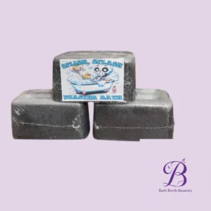 Three dark rectangular bath bombs stacked, one with a cartoon label reading 'SPLISH SPLASH TOASTER BATH' on a pale lavender background; Bath Bomb Beauties logo bottom right.