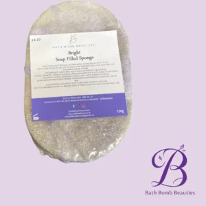 Round soap-filled sponge in clear wrap on a pale purple background; label reads 'Bright Soap Filled Sponge' by Bath Bomb Beauties with a purple logo.