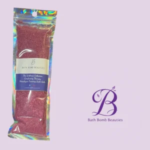 Holographic resealable bag of red bath salts labeled bath bomb beauties against a lavender background with a decorative logo in the corner