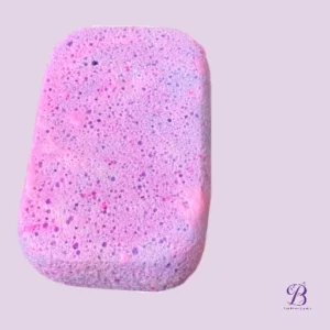 Pink and purple marbled bath sponge on a light lavender background with a decorative logo in the lower right corner