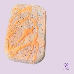 Slice of wholegrain bread with orange sauce drizzled in abstract patterns on a light lavender background with a small purple logo bottom right