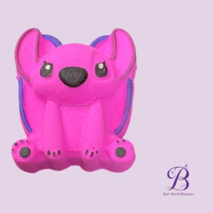 Pink dog-shaped bath bomb with purple accents on a lavender background, Bath Bomb Beauties logo in the corner.",