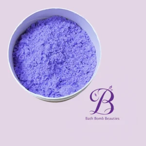 Lavender bath bomb crumble in a white tub on a light purple background with bath bomb beauties logo nearby