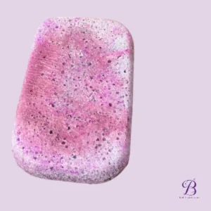 Pink speckled soap bar with purple and white flecks on a light lavender background.