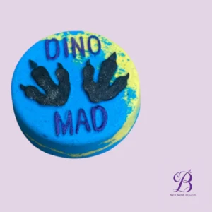 Blue round bath bomb with black dinosaur handprint designs and the words 'DINO MAD' on a lavender background.