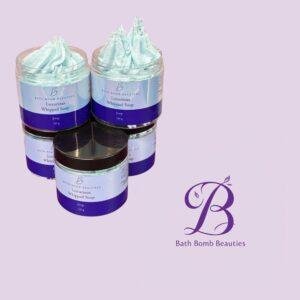 Two jars of Bath Bomb Beauties Luxurious Whipped Soap with pale blue swirls against a lavender background