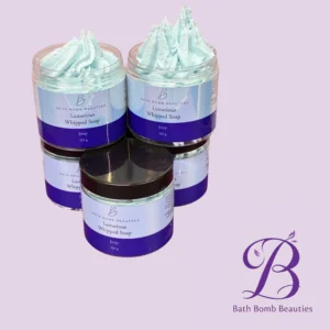 Two jars of Bath Bomb Beauties Luxurious Whipped Soap with pale blue whipped topping, set against a lavender background, showcasing the product.