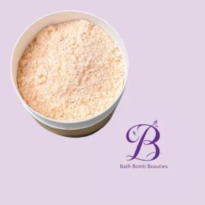 Round container of peach-colored bath powder on a pastel purple background; branding reads 'Bath Bomb Beauties' in purple script.