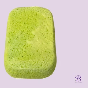 Green rectangular sponge with rounded corners on a light purple background