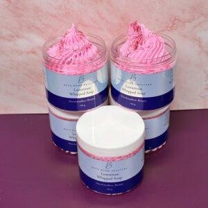 Four pink topped jars of luxurious whipped soap by bath bomb beauties displayed on a pink surface marshmallow boujee scent
