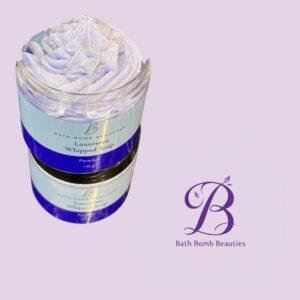 Jar of Luxurious Whipped Soap by Bath Bomb Beauties with lavender swirls, set against a lilac background next to the brand logo.