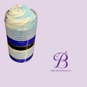 Jar of bath bomb beauties luxurious whipped soap with white and blue swirl set against a lavender background with a purple logo on the right