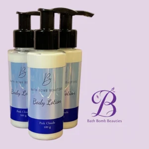 Three pump bottles of Bath Bomb Beauties body lotion in pastel blue and white with black pumps, labeled 'Body Lotion' and 'Pink Clouds' (100 g) against a pale lavender background with a purple 'B' logo nearby.