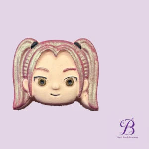 Close up of a pink glittery face mask design on a lavender background with bath bomb beauties logo in the bottom right