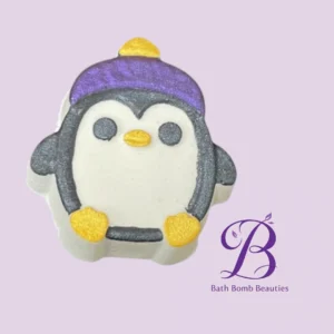 Penguin-shaped bath bomb with a purple hat and yellow feet on a lavender background, featuring the Bath Bomb Beauties logo top right.