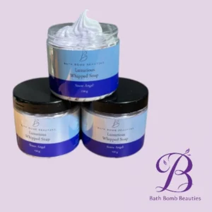 Three jars of Luxurious Whipped Soap (Snow Angel) from Bath Bomb Beauties stacked on a lavender background, with the Bath Bomb Beauties logo in the corner.