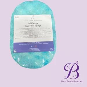 Turquoise oval soap-filled sponge bath bomb labeled 'Sol Carioca Soap Filled Sponge' on a lilac background, with Bath Bomb Beauties logo in the bottom right.