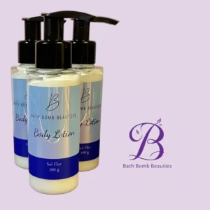 Three white lotion bottles with pump tops labeled "Bath Bomb Beauties" and "Body Lotion" against a light purple background, with a decorative purple logo in the corner.