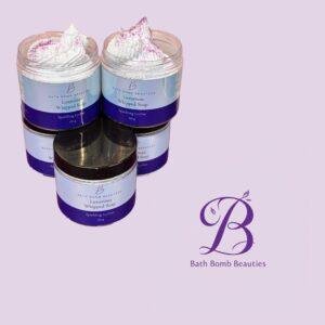 Two clear jars of Bath Bomb Beauties Luxurious Whipped Soap topped with white whipped cream and pink sprinkles, set against a lavender background.