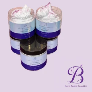Two lavender-purple jars of Bath Bomb Beauties Luxurious Whipped Soap with white whipped topping and pink sprinkles on top, against a lavender background.