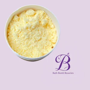 Round white tub filled with pale yellow bath powder on a lavender background, with Bath Bomb Beauties logo in purple.