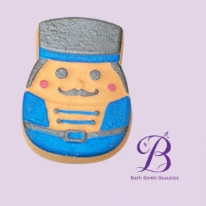Cartoon cookie shaped like a smiling man in a blue uniform with a top hat and mustache, on a lavender background with a Bath Bomb Beauties logo.
