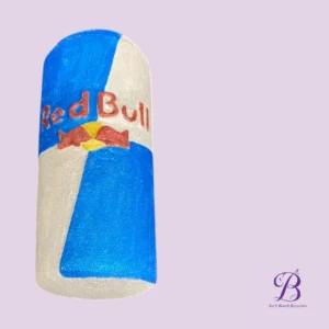 Bath bomb shaped like a red bull can blue and white panels with a red bow logo on a lavender background