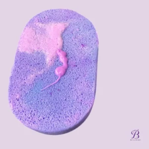 Purple and pink gradient bath sponge resting on a light lavender background.