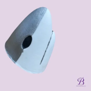 Close-up of a white and silver capsule-shaped object with a black circular hole on its side against a pale lavender background.