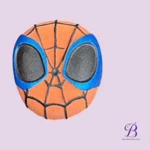 Spider-Man themed orange bath bomb with blue eye outlines and black web pattern on a lavender background.