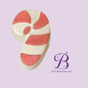 Pink and white striped bath bomb in a curved shape on a lavender background with Bath Bomb Beauties logo on the right.