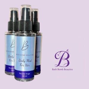 Three spray bottles labeled bath bomb beauties body mist for her baccarat rouge  ml on a lavender background with a purple bath bomb beauties logo nearby