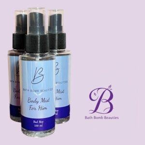 Three spray bottles with light blue labels reading bath bomb beauties body mist for him bad boy set against a pastel purple background with a purple bb logo