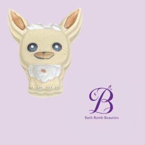 Cream-colored dog-shaped bath bomb with white foam on top and a white beard, set against a lavender background with Bath Bomb Beauties logo in the bottom right.